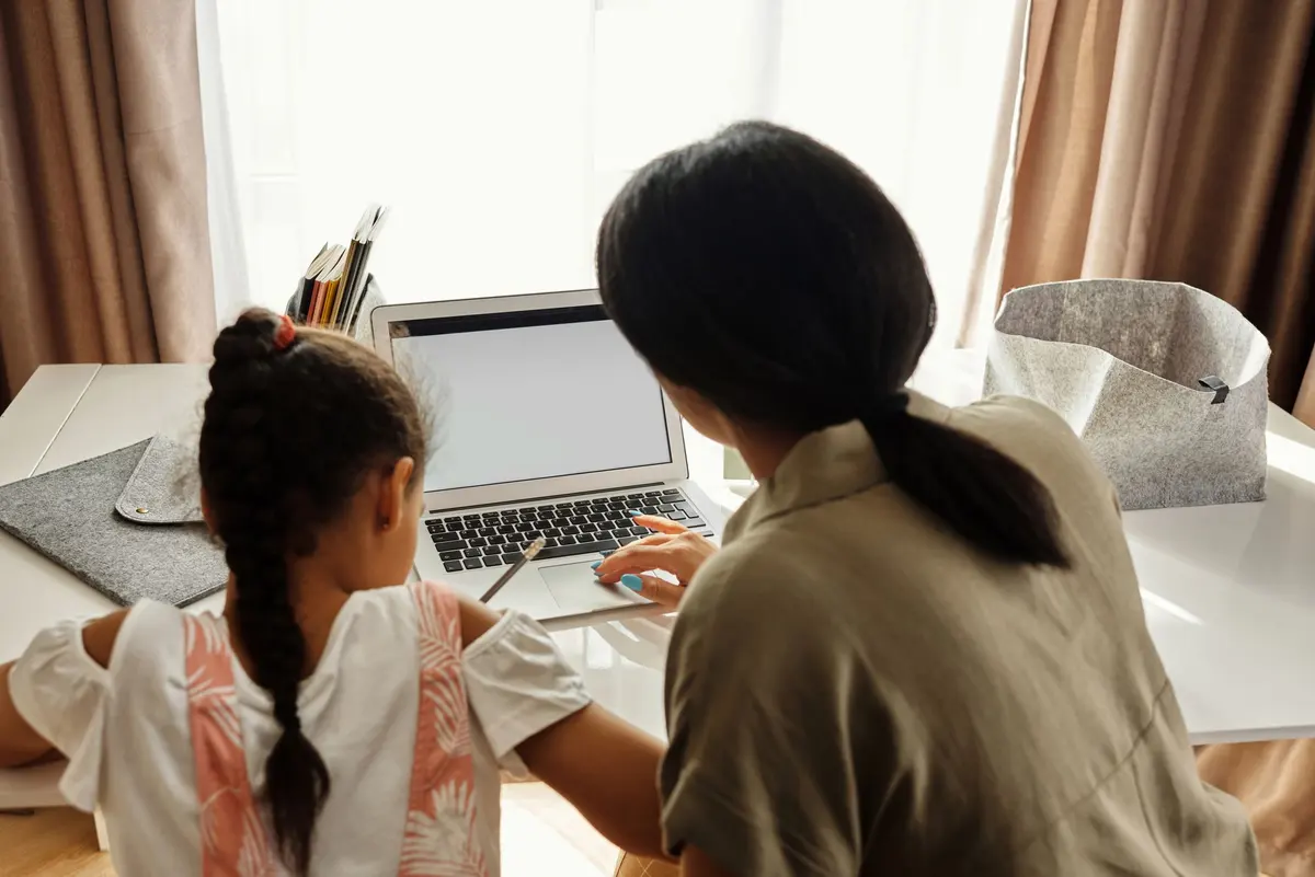 Une mère et sa fille, de dos, devant le même ordinateur portable